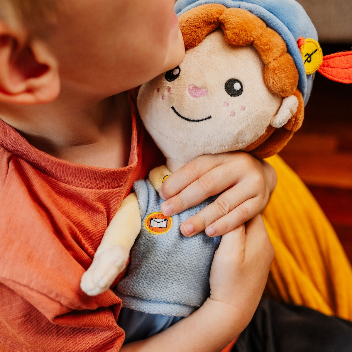 Kind knuffelt de Piet die 't Ziet-pop met blauwe muts en rode veer