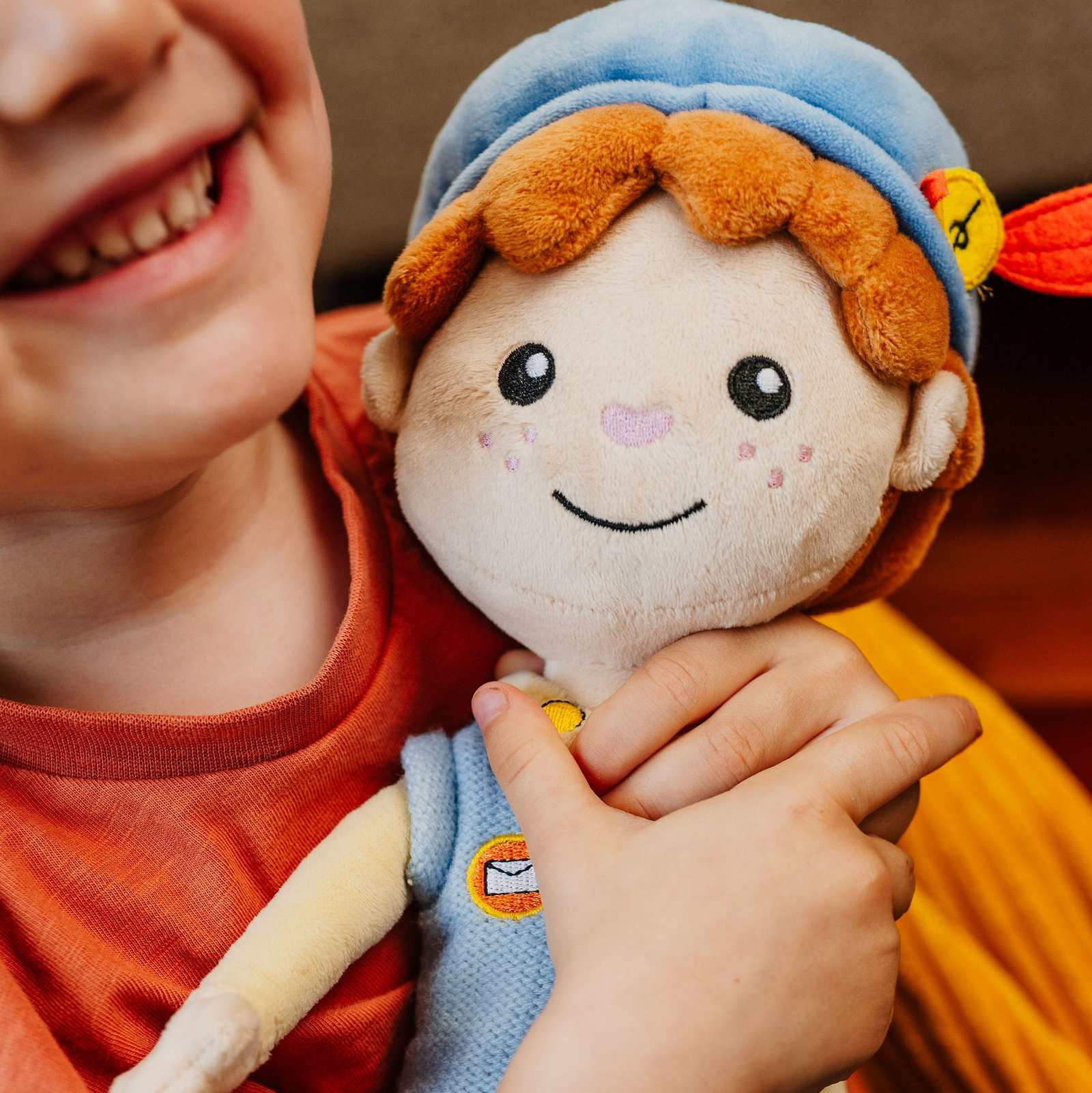Close-up van een lachend kind dat de Piet die 't Ziet-knuffel met postembleem vasthoudt