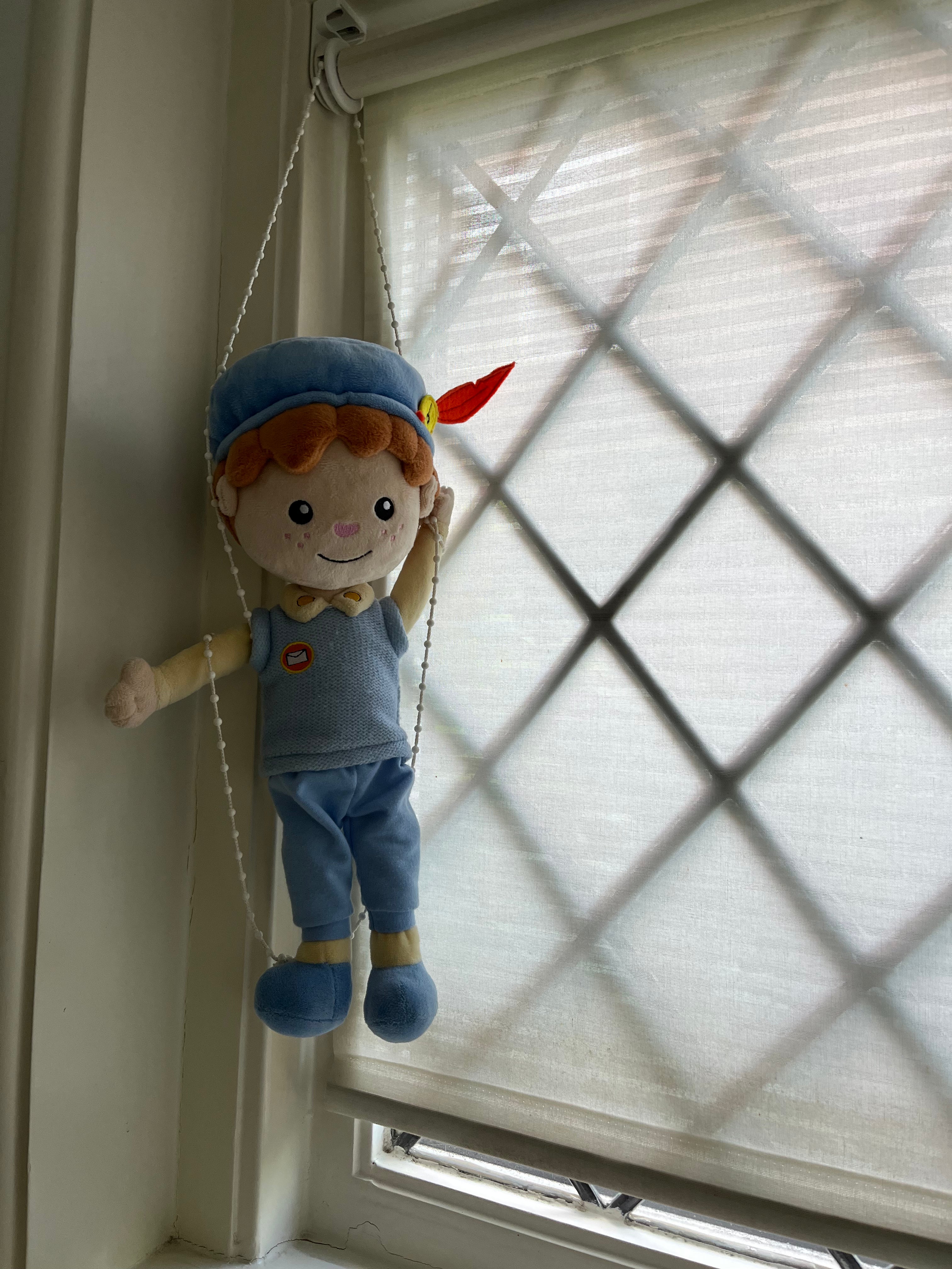 De Piet die 't Ziet-knuffel hangt aan het koordje van een rolgordijn voor het raam