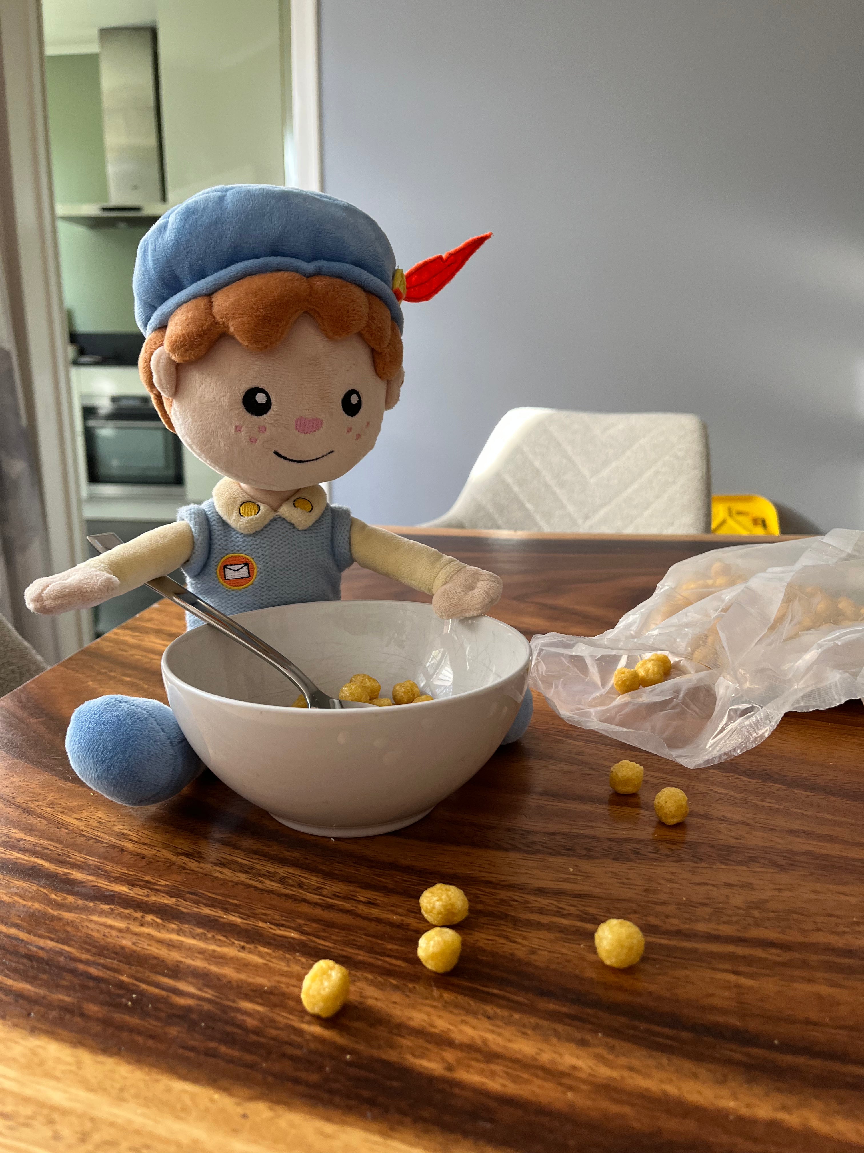 De Piet die 't Ziet-knuffel zit aan de eettafel met een kom cruesli op de keukentafel